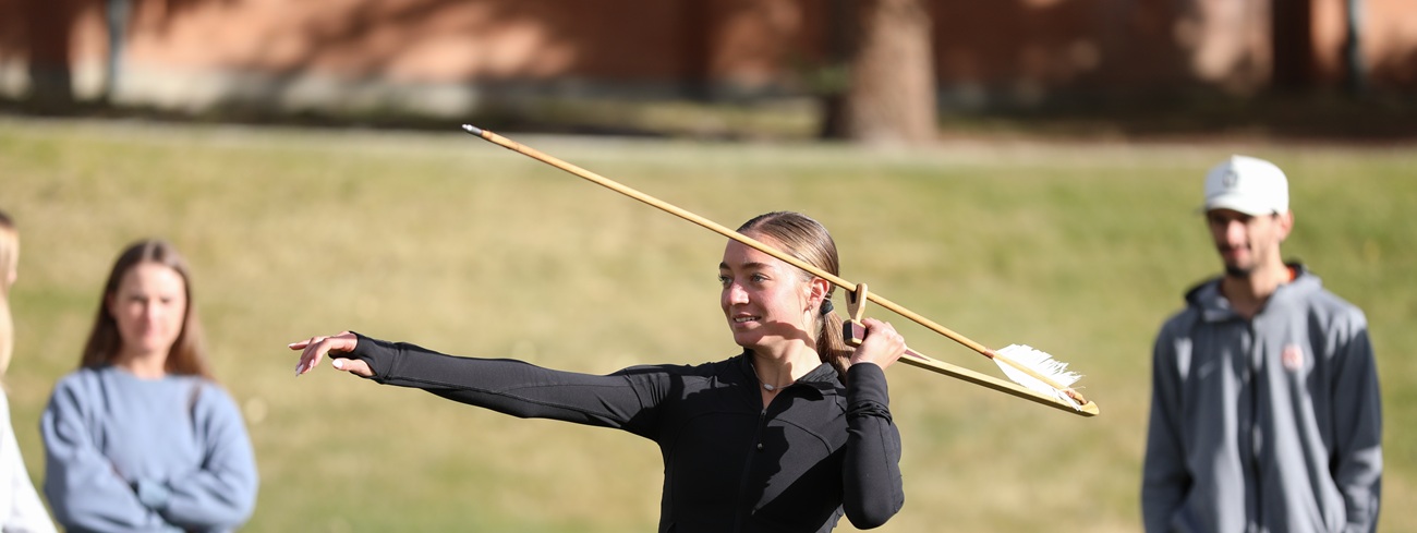 A student throws an atlatl. 