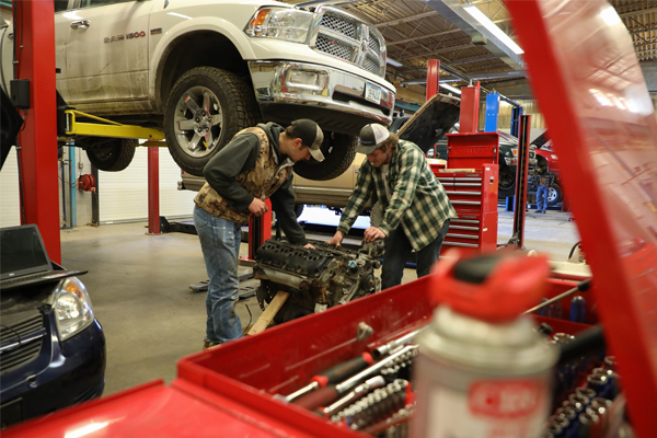 student working underneath a vehicle