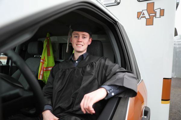 Trey Whitlock inside an ambulance while in his cap and gown.