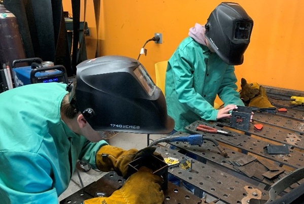 2 students work in welding helmets